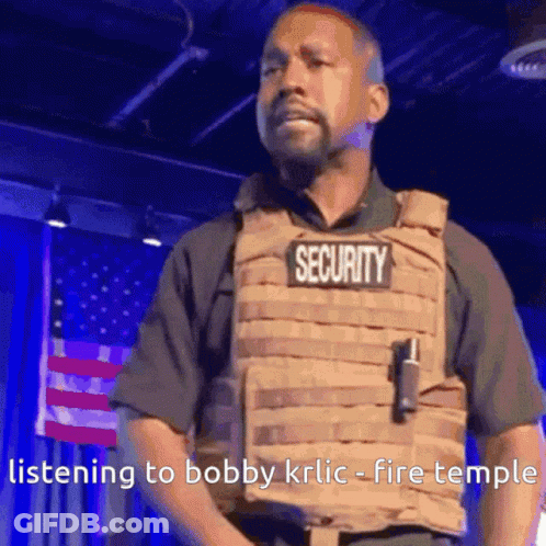 A Man Wearing A Security Vest Is Standing In Front Of An American Flag . GIF