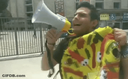 A Man Wearing A Sesame Street Shirt Holds A Megaphone GIF