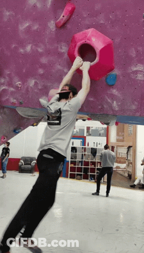 A Man Wearing A Shirt That Says ' Abercrombie & Fitch ' On It Climbs A Wall GIF