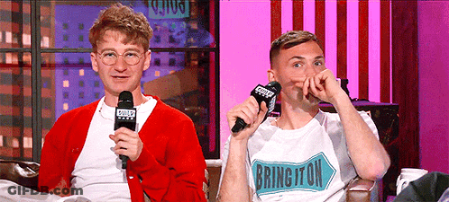 A Man Wearing A Shirt That Says Bringiton Is Sitting Next To Another Man GIF