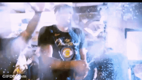 A Man Wearing A Shirt That Says Champions Is Standing In Front Of A Crowd GIF