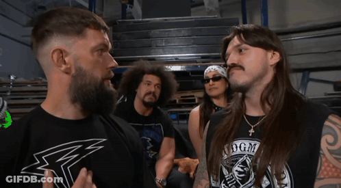 A Man Wearing A Shirt That Says Dgm Stands In Front Of Two Other Men GIF