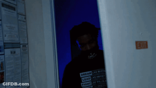 A Man Wearing A Shirt That Says Dream Like Martin Is Standing In A Dark Room GIF
