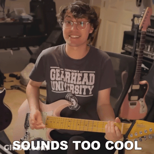 Man Holding Guitar With Gearhead University Shirt GIF