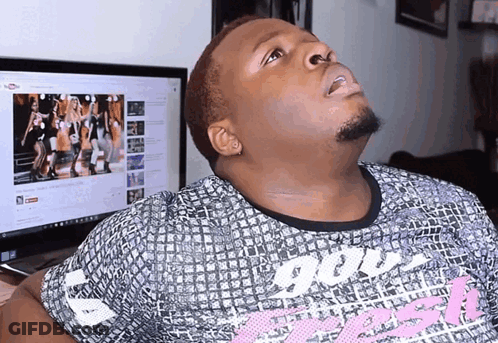 A Man Wearing A Shirt That Says ' God ' On It Looks Up At A Computer Screen GIF