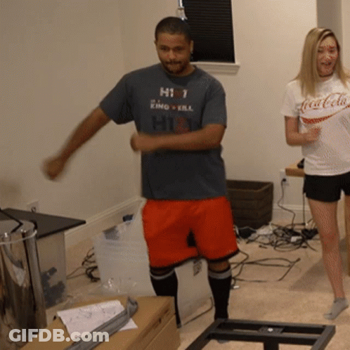 A Man Wearing A Shirt That Says Hit Is Dancing Next To A Woman Wearing A Coca-Cola Shirt GIF
