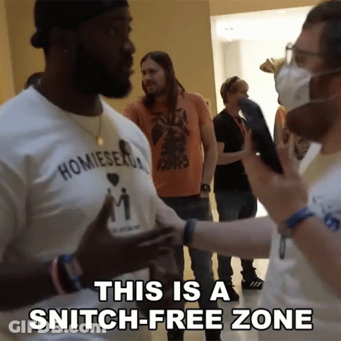A Man Wearing A Shirt That Says ' Homiesexual ' On It Talking To Another Man GIF