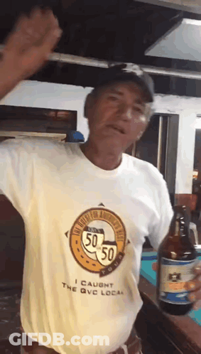 A Man Wearing A Shirt That Says I Caught The Qvc Local Is Holding A Bottle Of Beer GIF