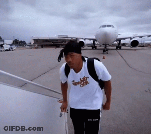 A Man Wearing A Shirt That Says ' Jungle ' On It Is Walking Towards An Airplane GIF