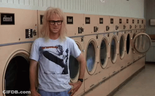 A Man Wearing A Shirt That Says Led Zeppelin Is Leaning Against A Washing Machine GIF
