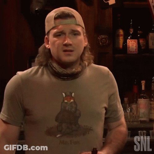 A Man Wearing A Shirt That Says Mr. Fox Is Standing In Front Of A Bar GIF