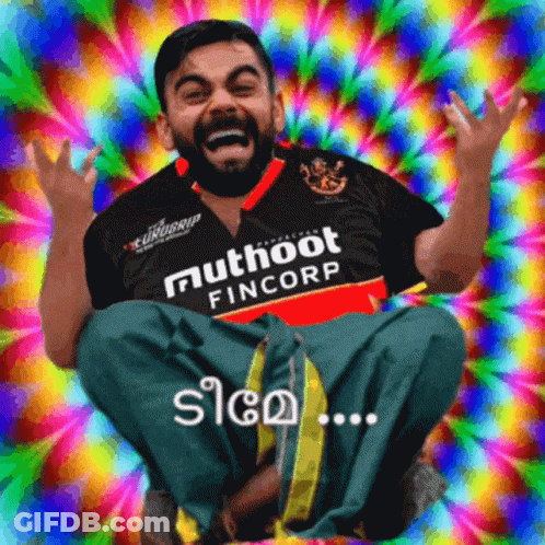 A Man Wearing A Shirt That Says Muthoot Fincorp Sits In Front Of A Colorful Background GIF