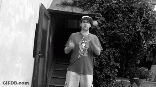 A Man Wearing A Shirt That Says New York Is Standing In Front Of A Doorway GIF
