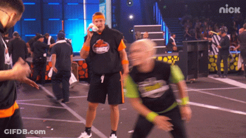 A Man Wearing A Shirt That Says ' Nick ' On It Stands On A Stage GIF
