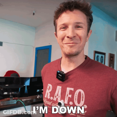 A Man Wearing A Shirt That Says R.a.f.o. Is Smiling GIF