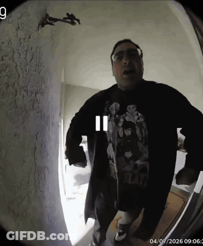 A Man Wearing A Shirt That Says Slash Stands In Front Of A Door GIF