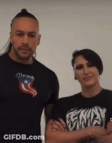 A Man Wearing A Shirt That Says Strong Stands Next To A Woman Wearing A Shirt That Says Ena GIF