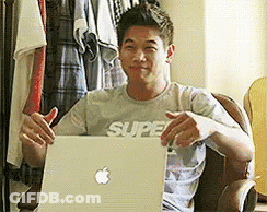 A Man Wearing A Shirt That Says Super Is Sitting In Front Of A Laptop GIF