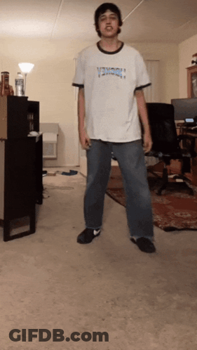 A Man Wearing A Shirt That Says Thrasher Is Standing In A Room GIF