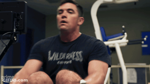 A Man Wearing A Shirt That Says Wilderness On It Sits On A Machine GIF
