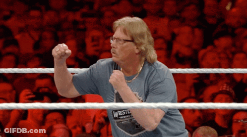 A Man Wearing A Shirt That Says Wrestle Is Standing In A Wrestling Ring GIF