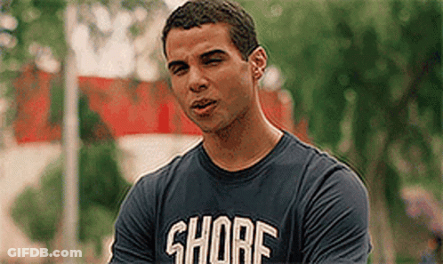 A Man Wearing A Shore T-Shirt Is Standing In Front Of Trees . GIF