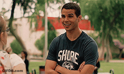 A Man Wearing A Shore T-Shirt Is Talking To A Woman In A Park . GIF