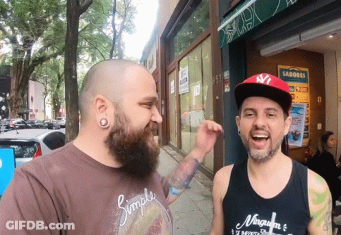 A Man Wearing A Simple Shirt Is Standing Next To Another Man Wearing A Ny Hat GIF