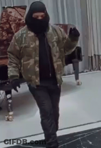 A Man Wearing A Ski Mask And A Camouflage Jacket Is Standing In Front Of A Piano . GIF