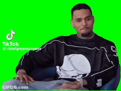 A Man Wearing A Skull Shirt Is Sitting In A Chair With His Hands On His Knees . GIF
