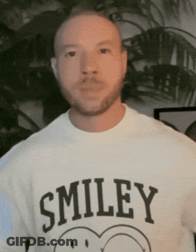 A Man Wearing A Smiley T-Shirt With A Smiley Face On It GIF