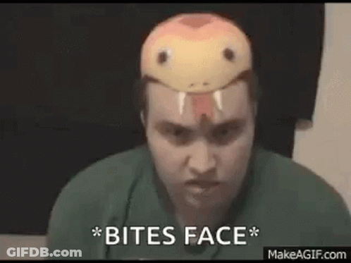 A Man Wearing A Snake Mask On His Head Is Biting His Face . GIF
