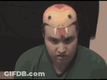 A Man Wearing A Snake Mask On His Head Is Looking At The Camera GIF