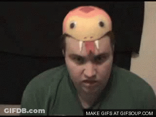 A Man Wearing A Snake Mask On His Head Is Making A Funny Face . GIF