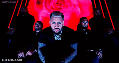 A Man Wearing A Solo Necklace Stands In Front Of A Group Of Men GIF
