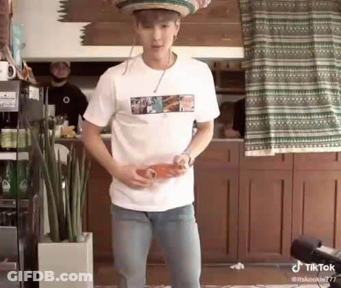 A Man Wearing A Sombrero And A White Shirt Is Holding A Bottle Of Soda . GIF
