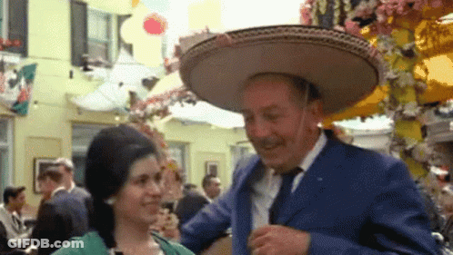 A Man Wearing A Sombrero Is Dancing With A Woman In A Green Dress GIF