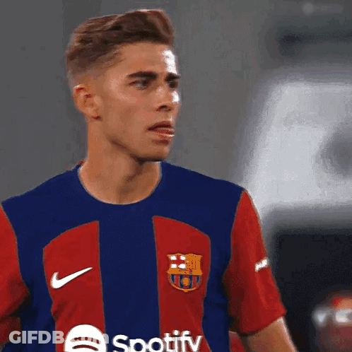 A Man Wearing A Spotify Shirt Looks At Something GIF