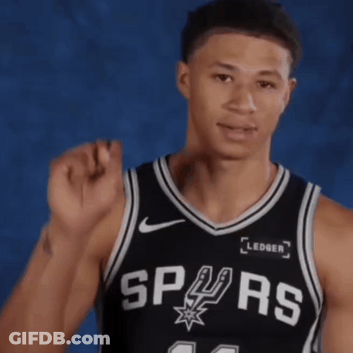 A Man Wearing A Spurs Jersey Holds His Fist Up In The Air GIF