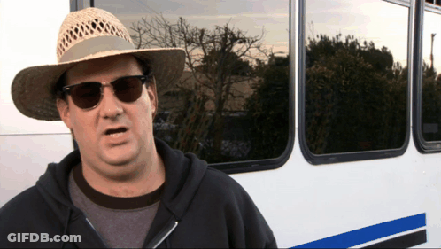 A Man Wearing A Straw Hat And Sunglasses Is Standing In Front Of A Bus GIF