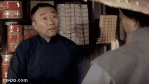 A Man Wearing A Straw Hat Talks To Another Man GIF