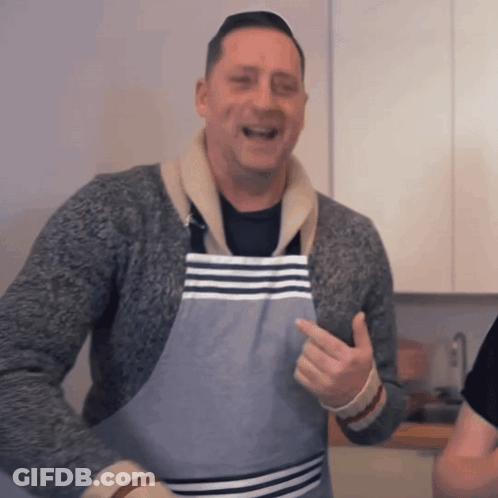 A Man Wearing A Striped Apron Is Pointing GIF