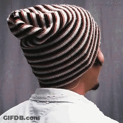 A Man Wearing A Striped Beanie Is Looking To The Side GIF