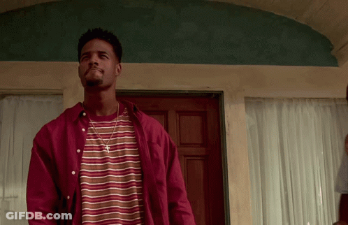 A Man Wearing A Striped Shirt And A Red Shirt Is Standing In Front Of A Door GIF
