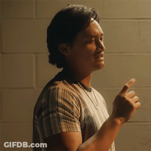 A Man Wearing A Striped Shirt Is Pointing At Something GIF