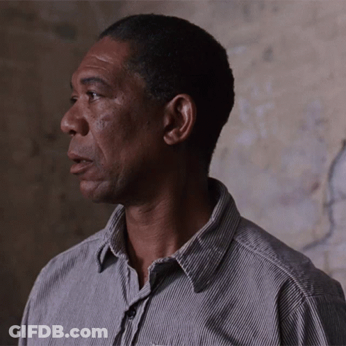 A Man Wearing A Striped Shirt Looks To His Left GIF