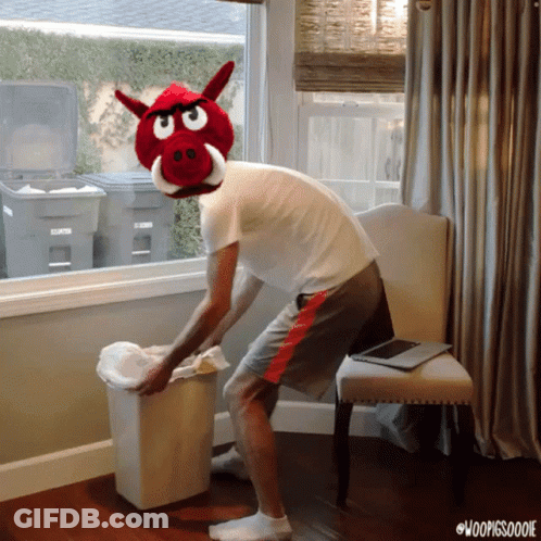A Man Wearing A Stuffed Pig Head Throws A Trash Can GIF