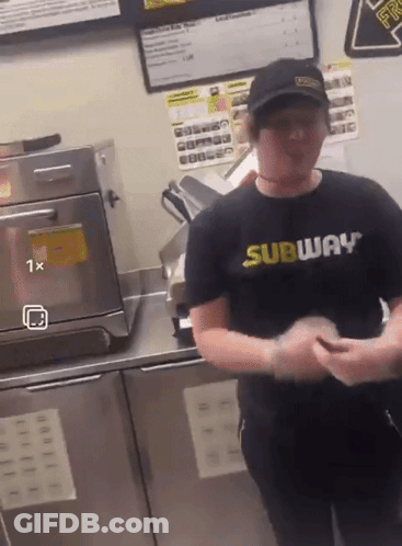 A Man Wearing A Subway Shirt Is Standing In Front Of An Oven GIF