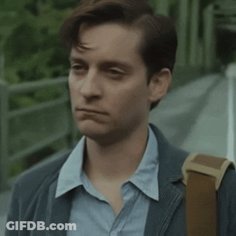A Man Wearing A Suit And A Blue Shirt Is Walking Down A Sidewalk With A Backpack . GIF