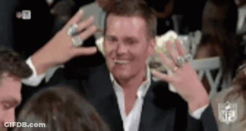 A Man Wearing A Suit And A White Shirt Is Surrounded By People With Their Hands In The Air . GIF